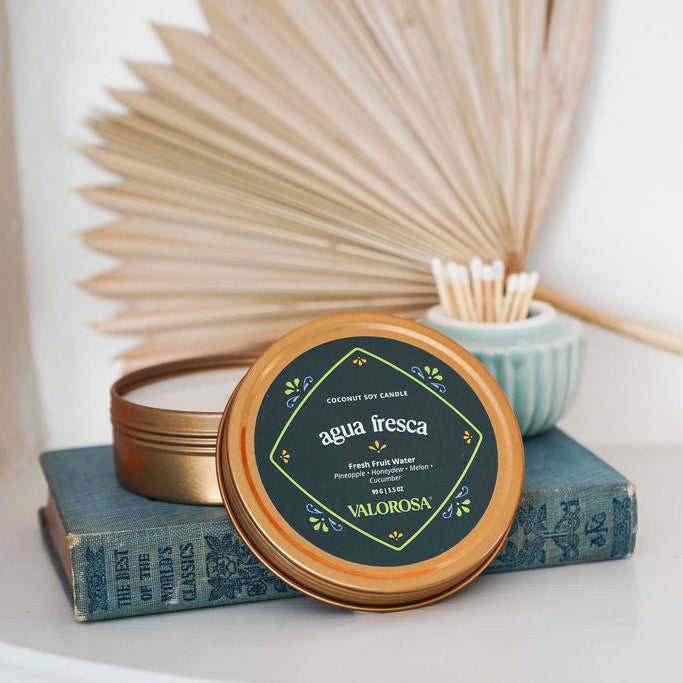 Agua Fresca Candle Tin on top of a blue book 