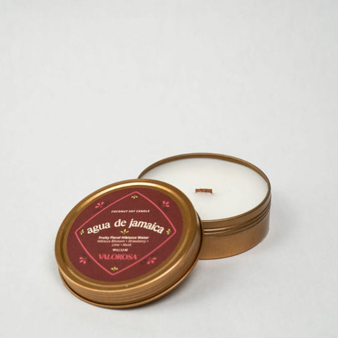 Round candle in a gold tin with a red label on a white background