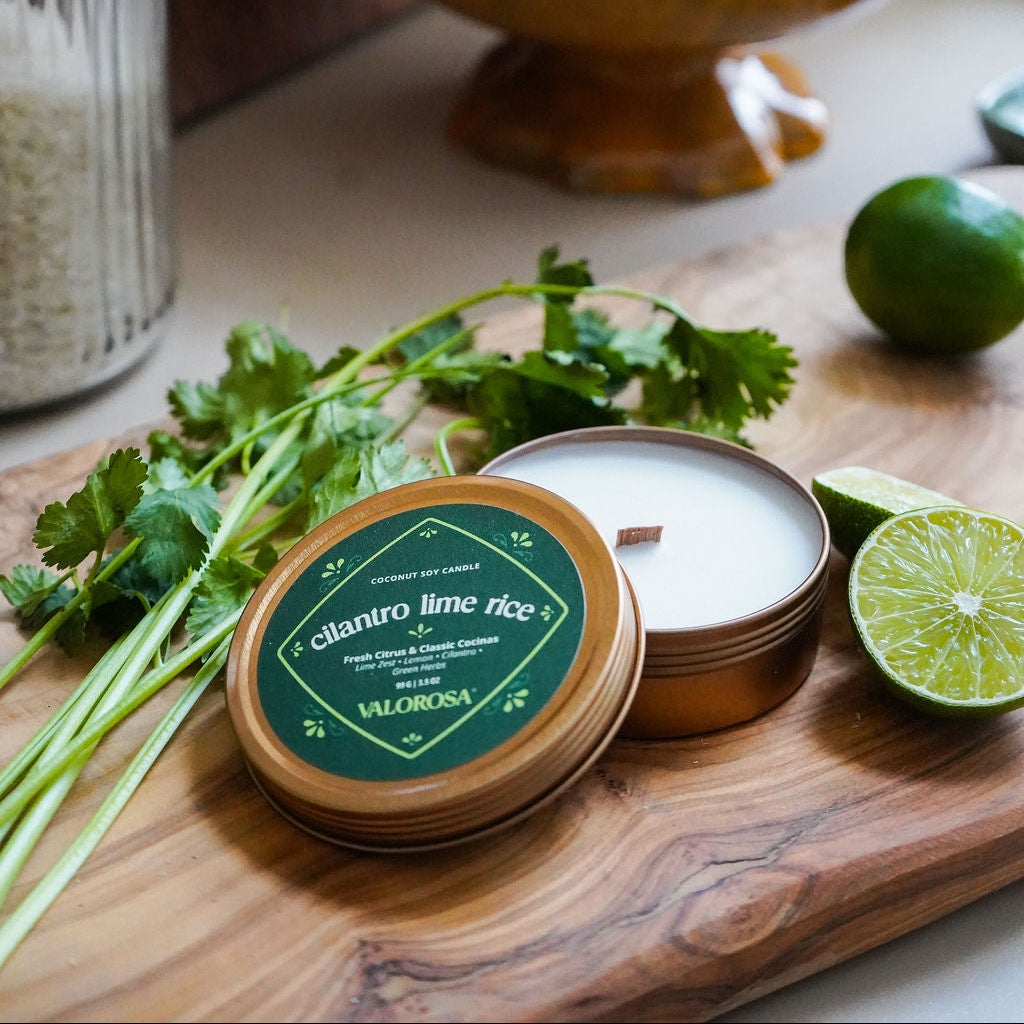 Candle with cilantro lime rice flavor on a wooden board with lemons and limes in the background.