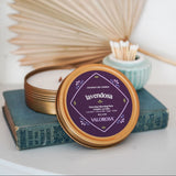 Lavendosa Candle Tin with 'Valorosa' branding on a white surface with dried plants and books.
