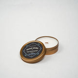 Candle in a bronze tin with a black label on a white background