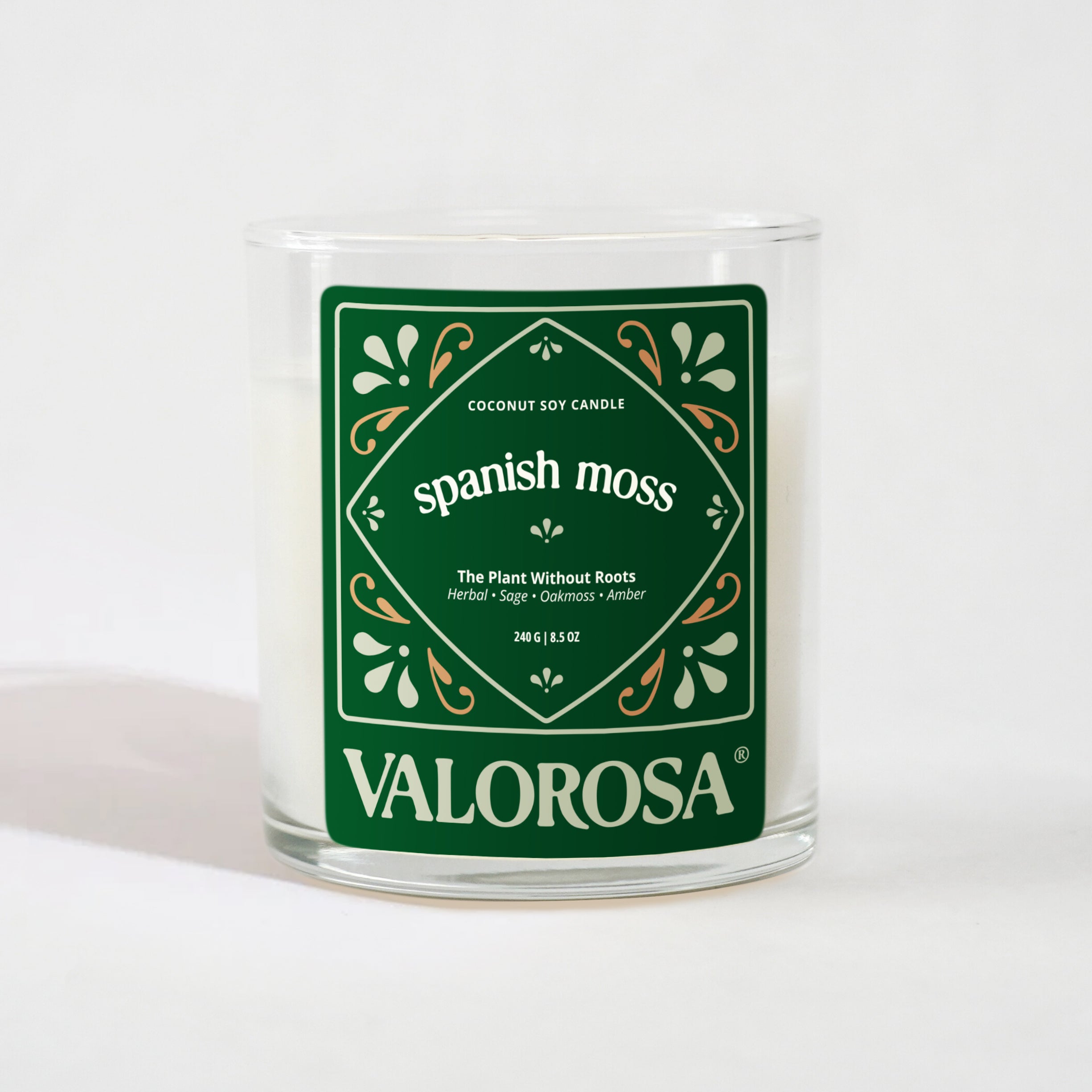 Candle with a green label reading 'Spanish Moss' by Valorosa on a white background