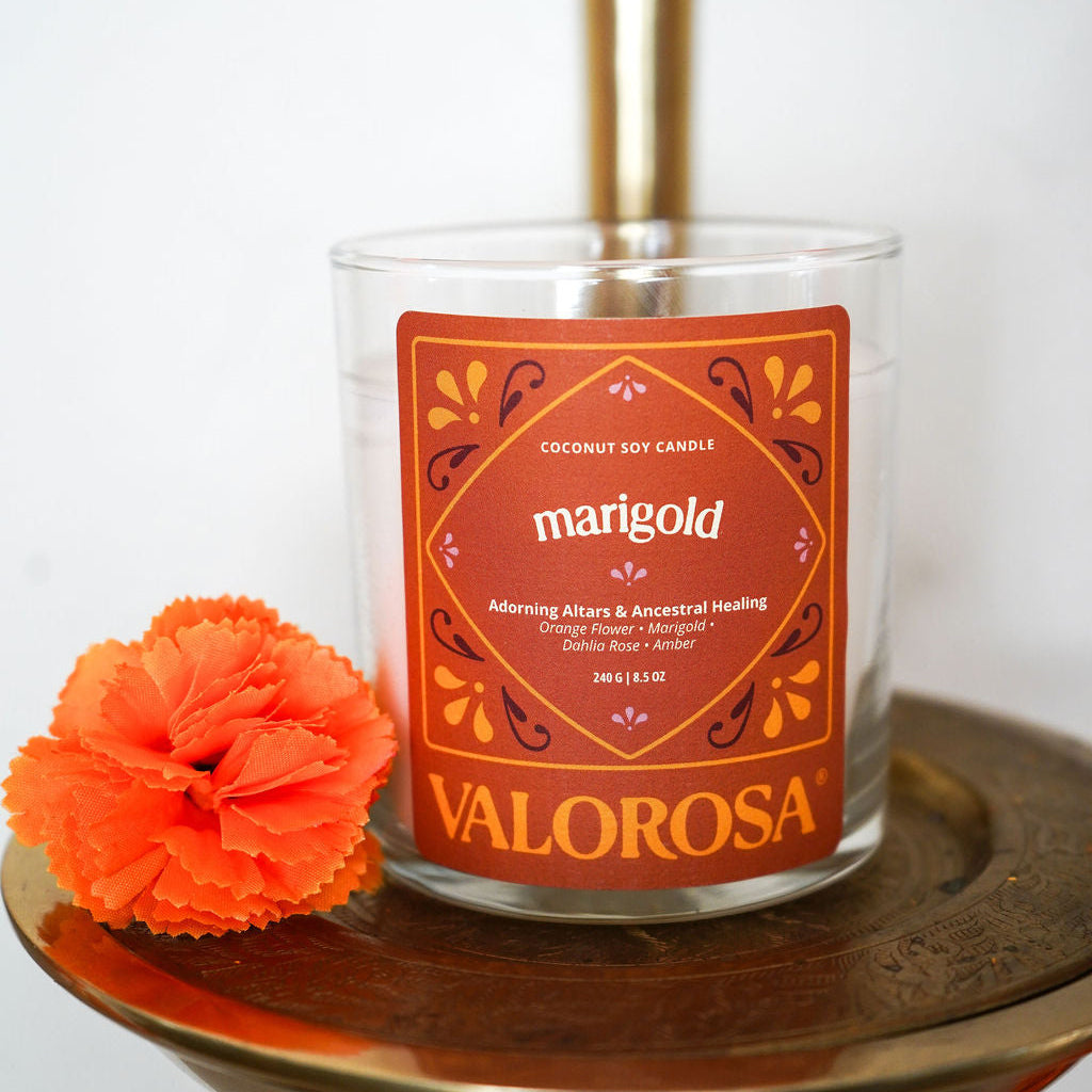 Valorosa marigold candle on a small table with an orange marigold flower