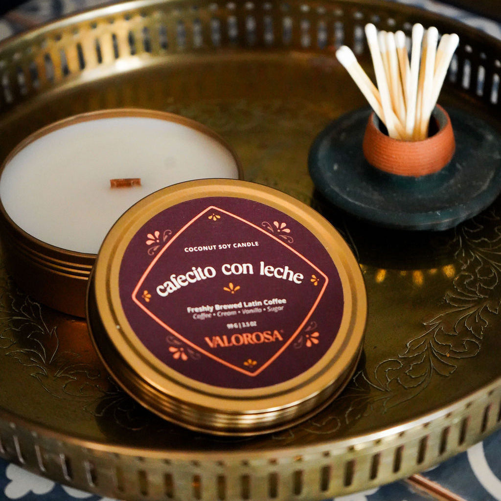 Candle with a decorative lid on a gold tray with a blue patterned surface