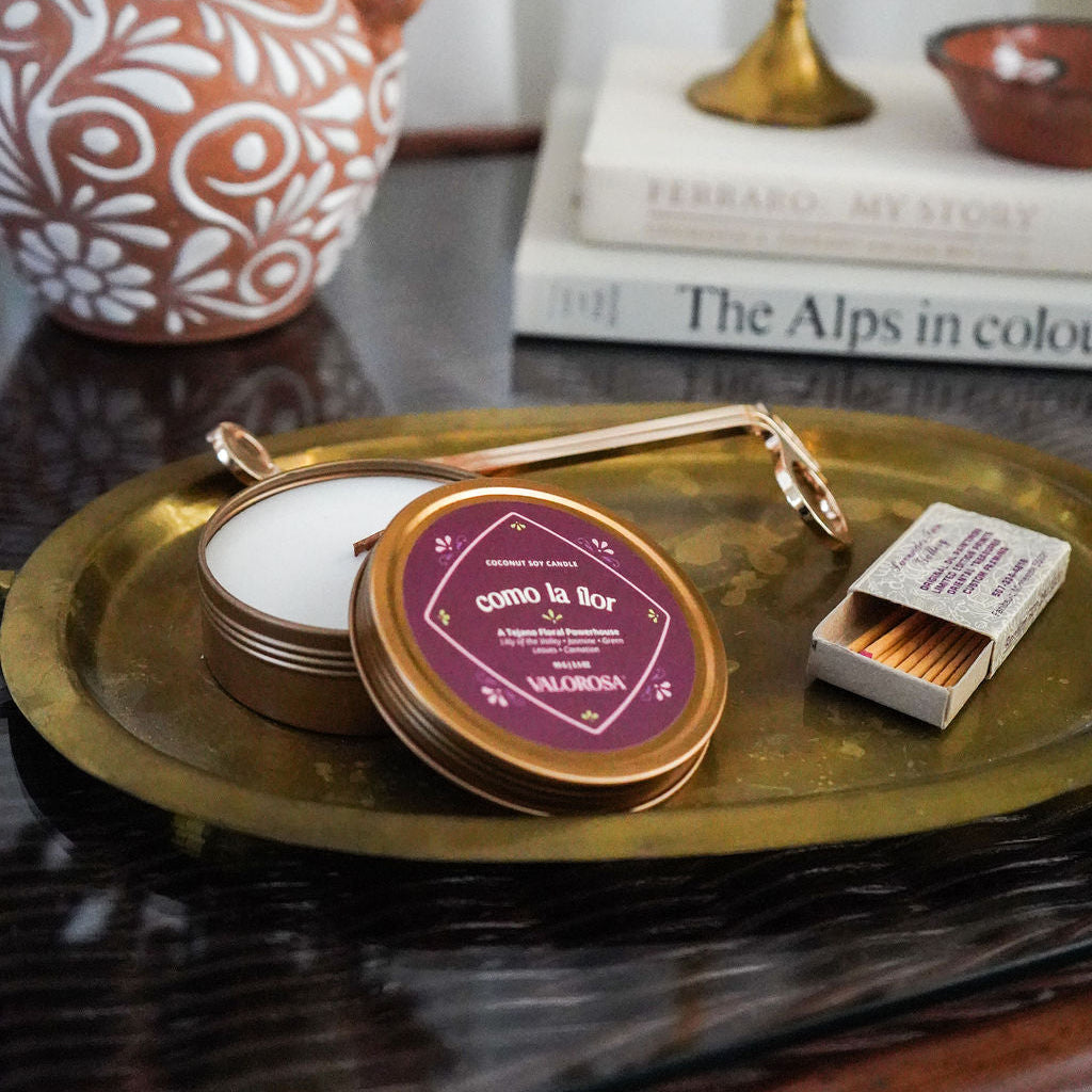 Decorative tray with a candle, matches, and a decorative item on a table.