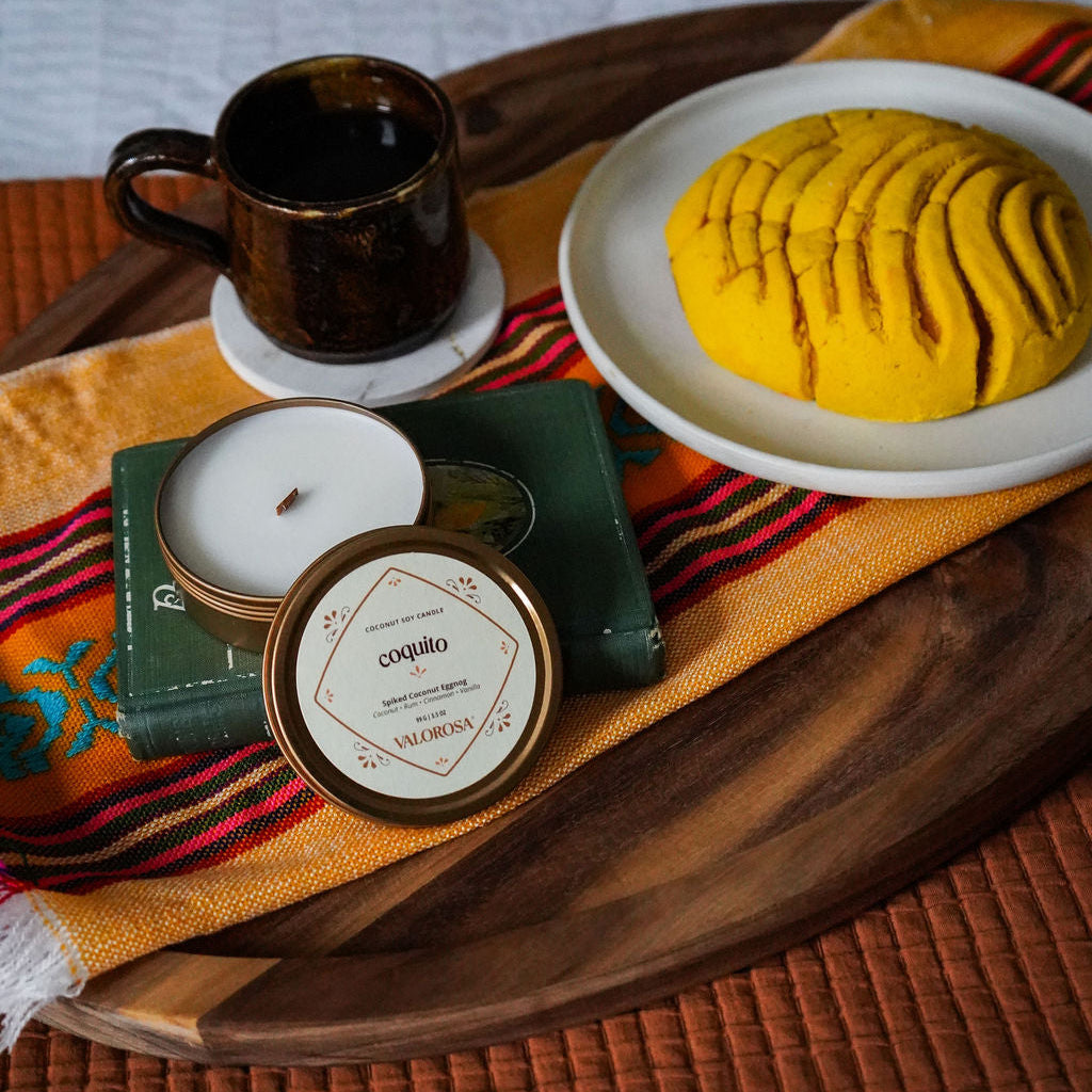 Tray with a cup, plate of food, and a coquito candle on a textured surface