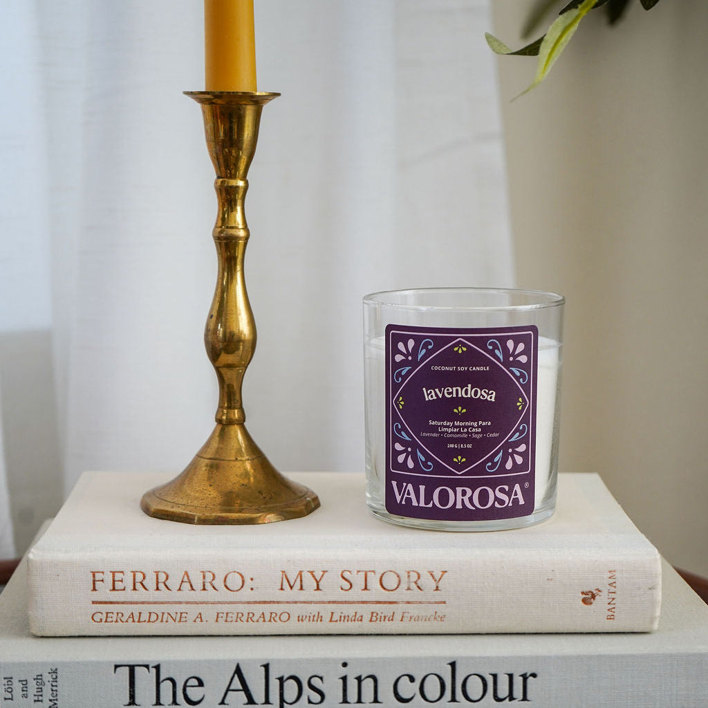 Lavendosa Candle on books with a brass candlestick and decorative items.
