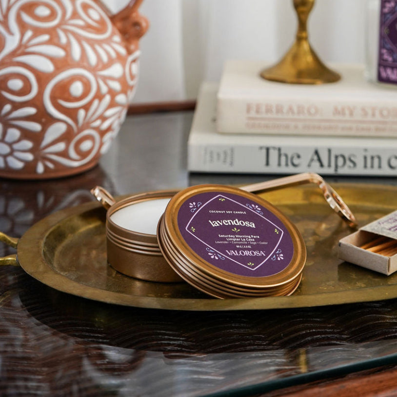 Decorative setting with a vase of flowers, books, and a tray with purple containers on a table.