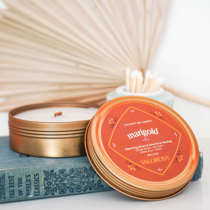 Marigold candle tin with wooden sticks on a white surface on top of a blue book