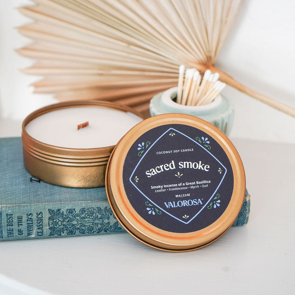 sacred smoke candle tin on a white surface and wooden fan in background